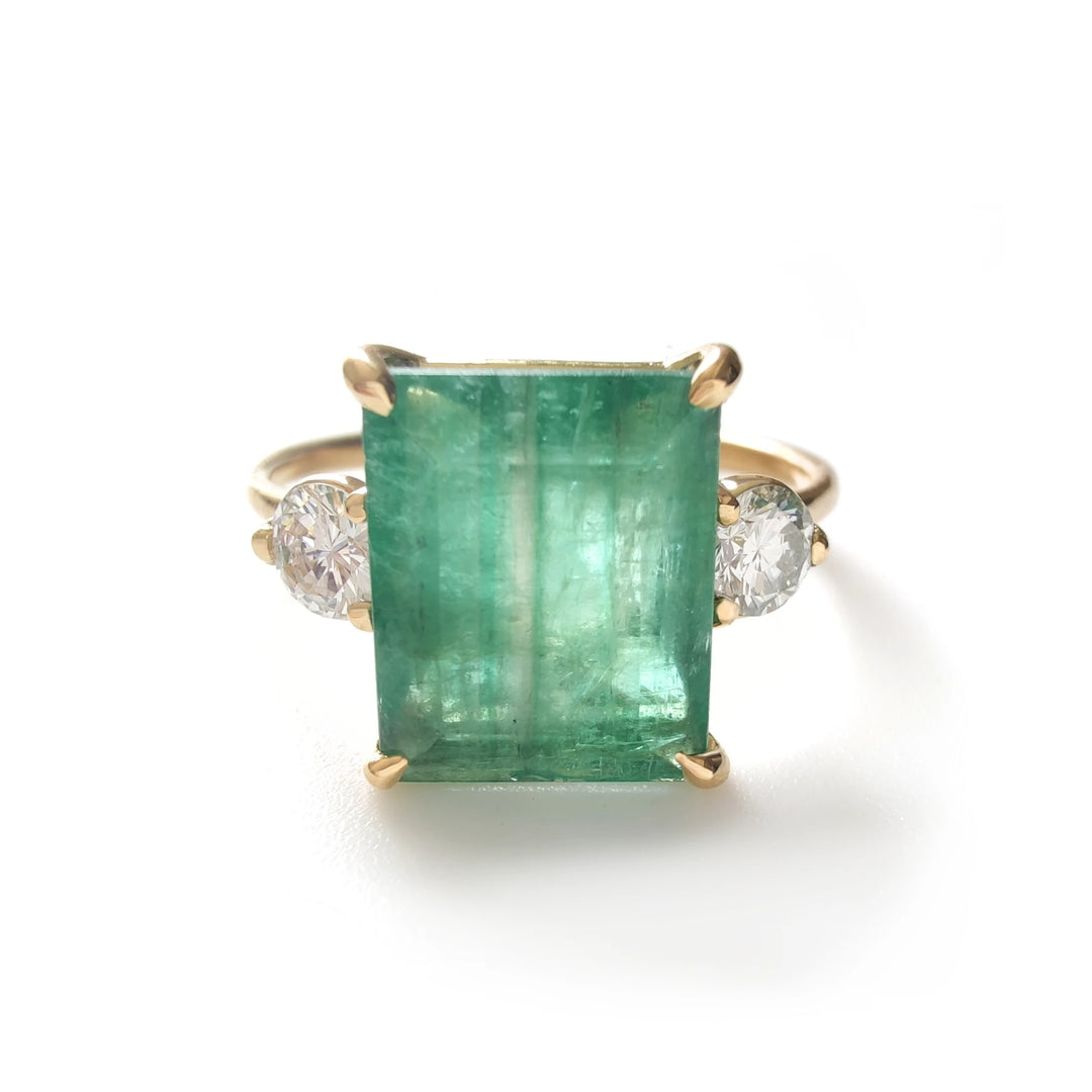 Front view of 18K yellow gold three-stone ring with emerald cut emerald and side diamonds