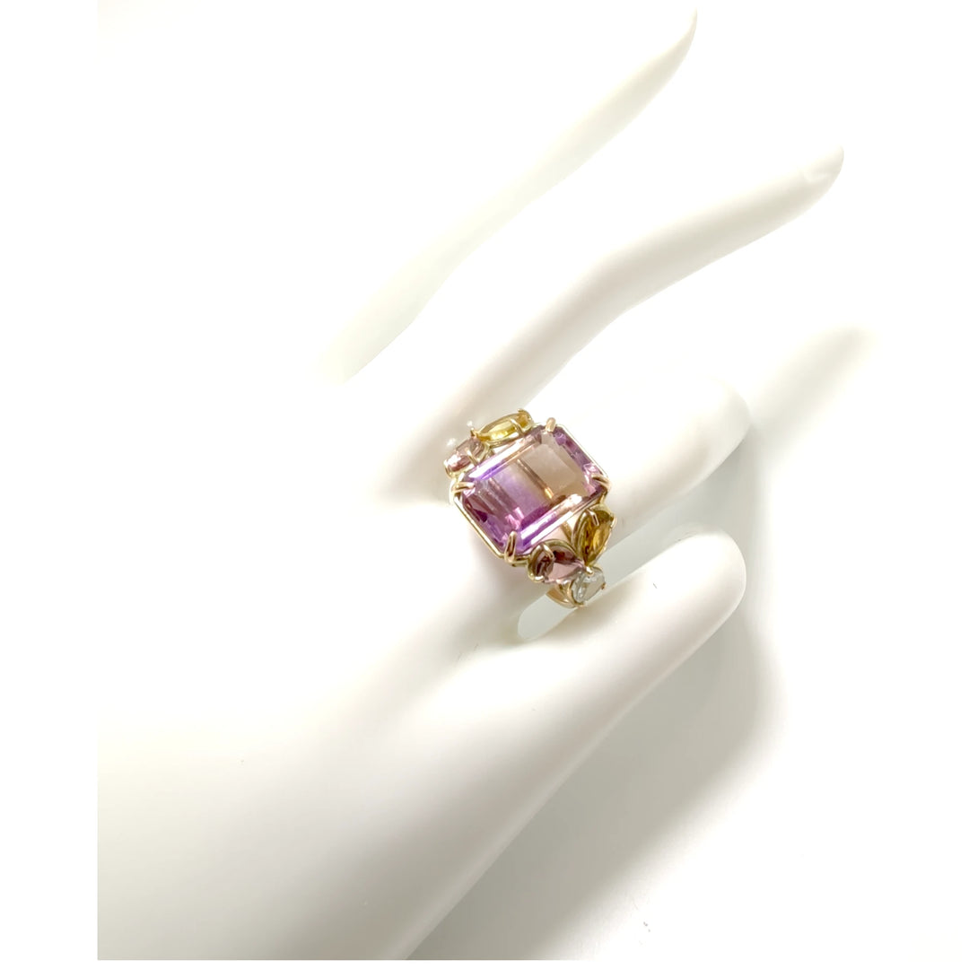 Elegant cocktail ring in 14K yellow gold with a central ametrine, accented by amethysts and aquamarines, displayed on a mannequin hand