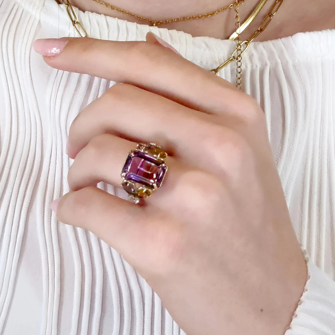 Singular cocktail ring in 14K yellow gold with a central ametrine, flanked by pear-shaped amethysts and aquamarines, displayed on a model’s hand