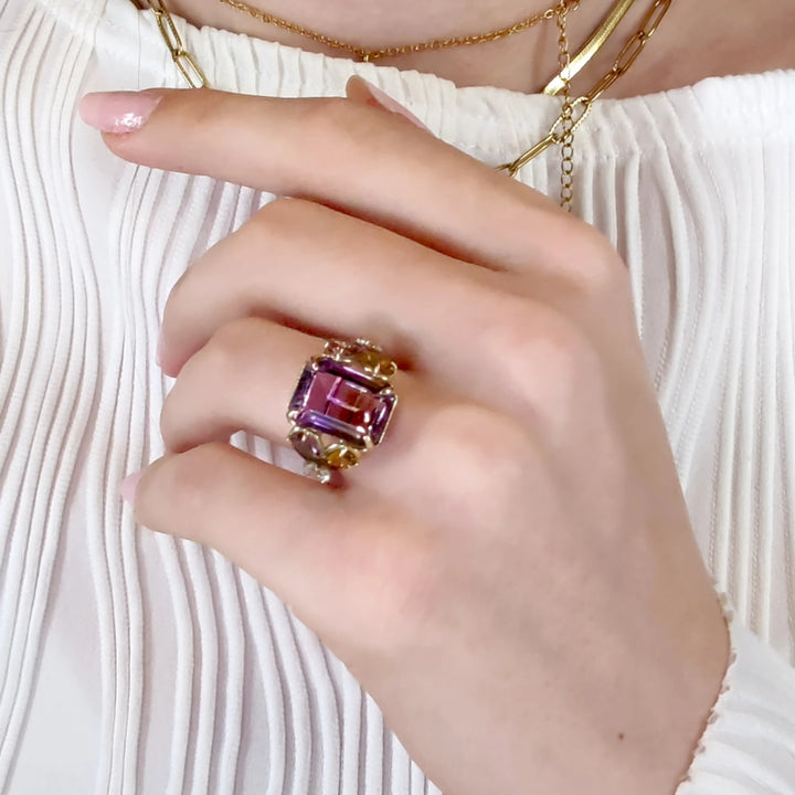 Singular cocktail ring in 14K yellow gold with a central ametrine, flanked by pear-shaped amethysts and aquamarines, displayed on a model’s hand