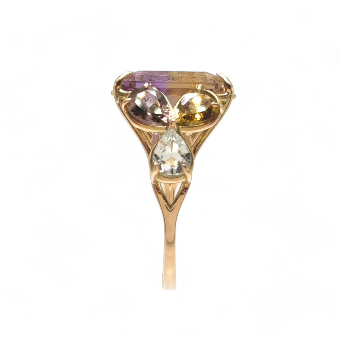 Vertical side view of an artistic 14K yellow gold cocktail ring with a central ametrine, framed by pear-shaped amethysts and aquamarines, perfect gift