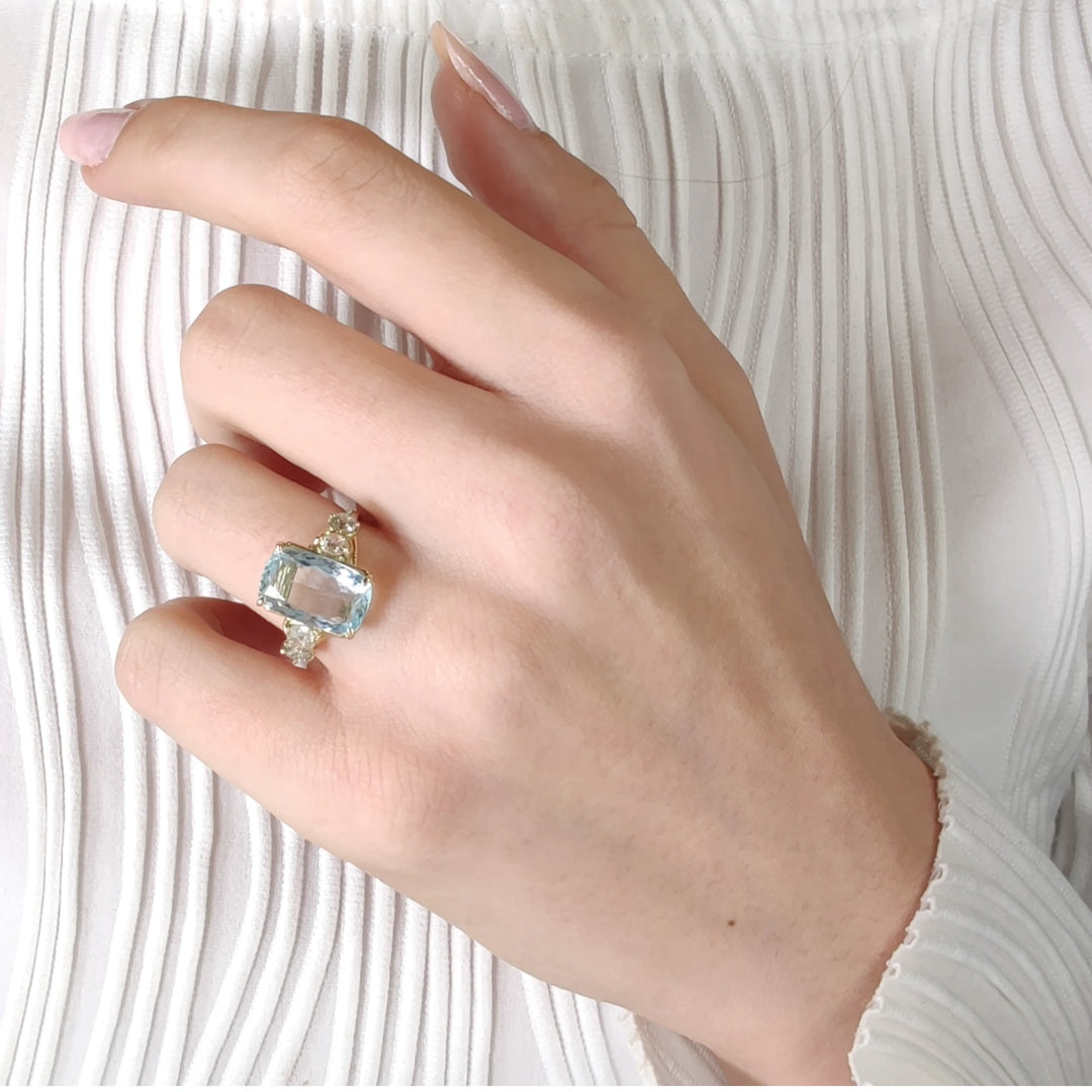 14K yellow gold aquamarine ring with diamonds, worn gracefully on a model’s hand