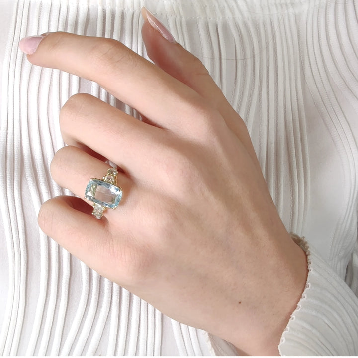 14K yellow gold aquamarine ring with diamonds, worn gracefully on a model’s hand