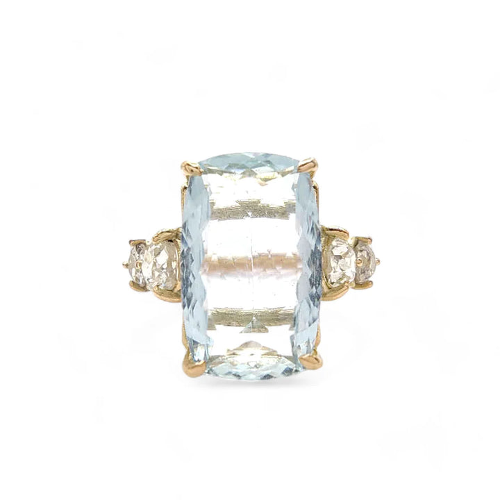 Front view of a 14K yellow gold ring with a central aquamarine and two brilliant-cut diamonds on each side