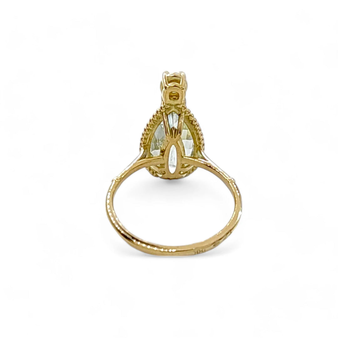 Back view of a women’s 18K yellow gold ring with a pear-cut aquamarine centerpiece and a brilliant diamond