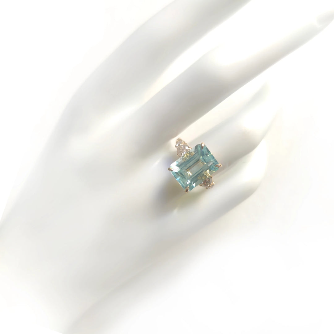 full view of a womenβs 18K yellow gold cocktail ring with aquamarine and diamonds displayed on a mannequin hand