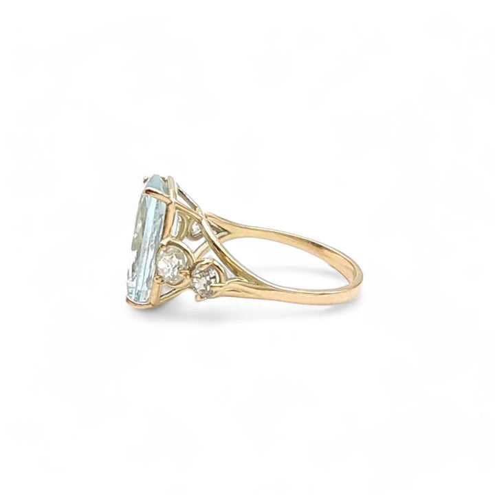 Left side view of a 14K yellow gold ring featuring a cushion-cut aquamarine with diamond accents.
