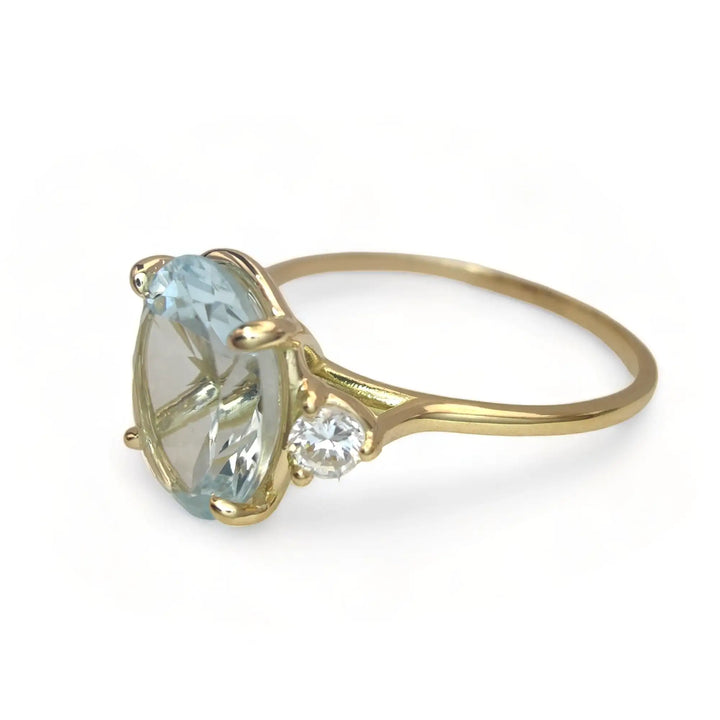 Left side view of a handcrafted 18K yellow gold three-stone ring with an aquamarine and diamond accents