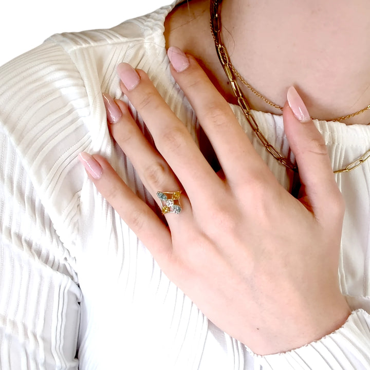 Second pose of a model's hand showcasing a 14K yellow gold engagement ring with a combination of brilliant and marquise diamonds, arranged in a striking cross design.