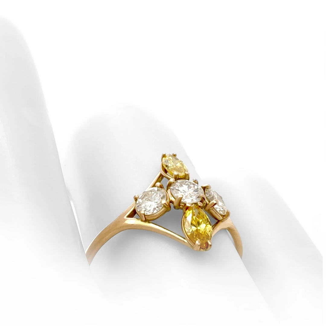 Close-up view on a mannequin hand of a 14K yellow gold engagement ring displaying a cross pattern with brilliant and fancy yellow marquise diamonds