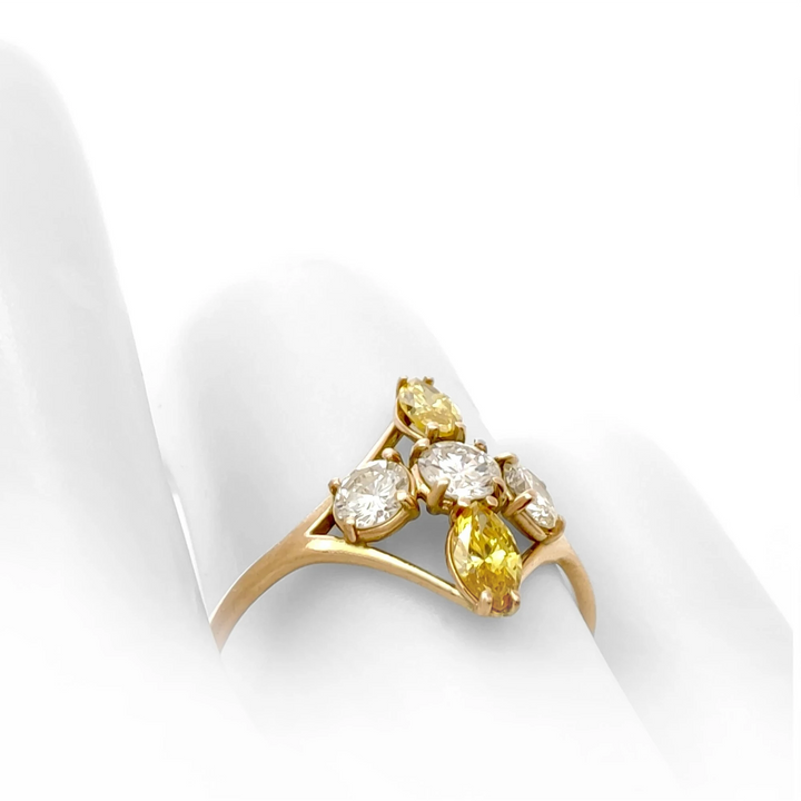 Close-up view on a mannequin hand of a 14K yellow gold engagement ring displaying a cross pattern with brilliant and fancy yellow marquise diamonds