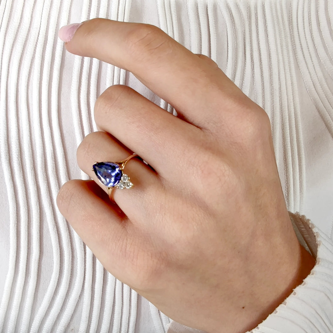 Second pose of a model displaying a 14K yellow gold engagement ring with a pear-cut tanzanite and three diamonds, emphasizing the ring's unique design and appeal