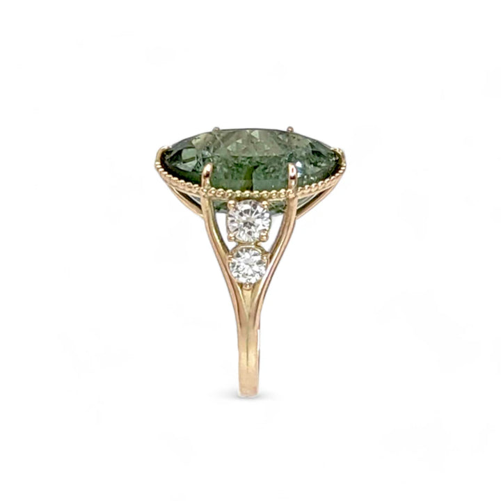 Vertical side view of a 14K yellow gold cocktail ring with an oval green tourmaline and diamonds, emphasizing the elegant miligrain detailing and contemporary style