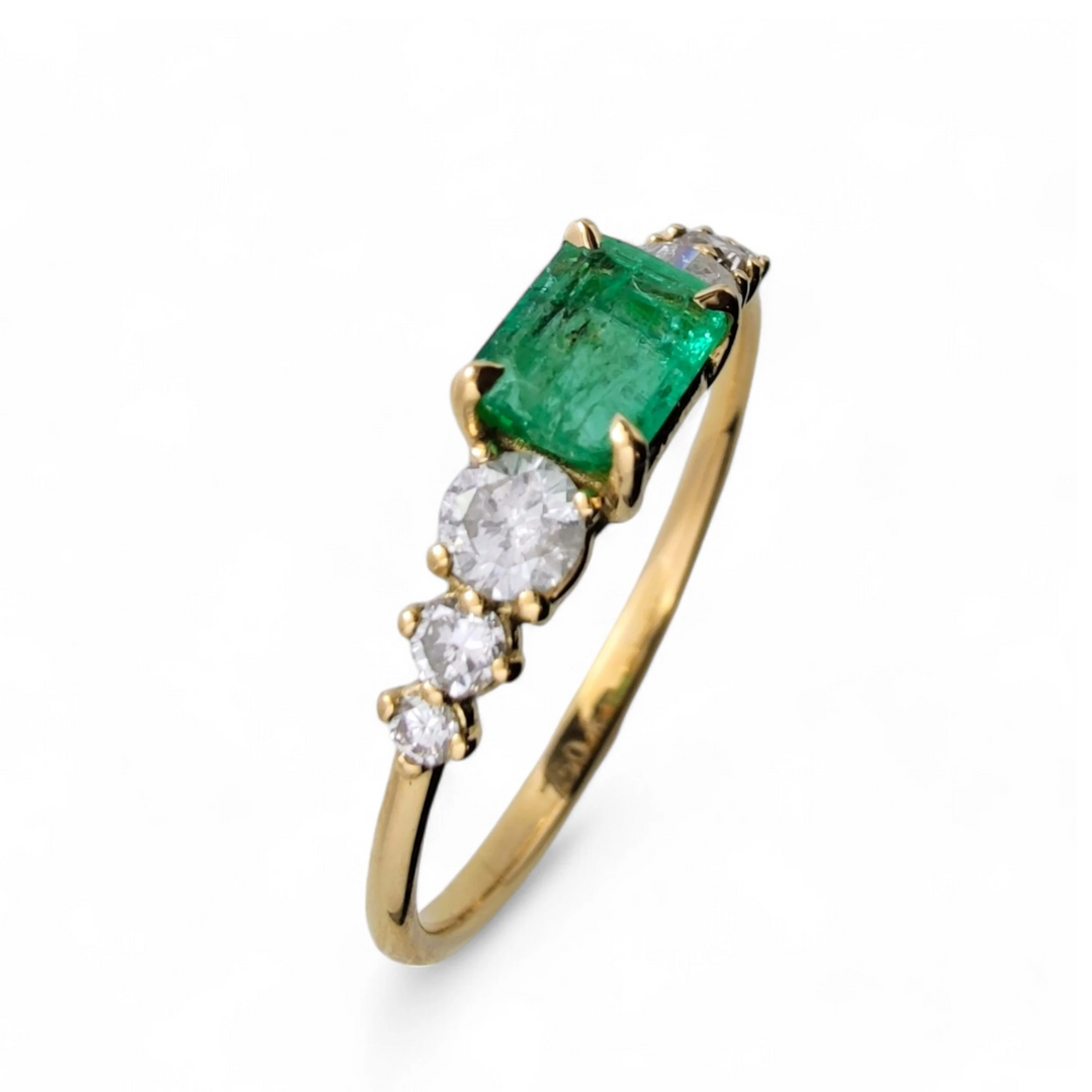 Vertical perspective view of a womenâs 18K solid yellow gold ring with a central emerald and three diamonds on each side