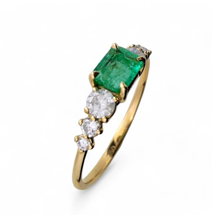Vertical perspective view of a womenâs 18K solid yellow gold ring with a central emerald and three diamonds on each side