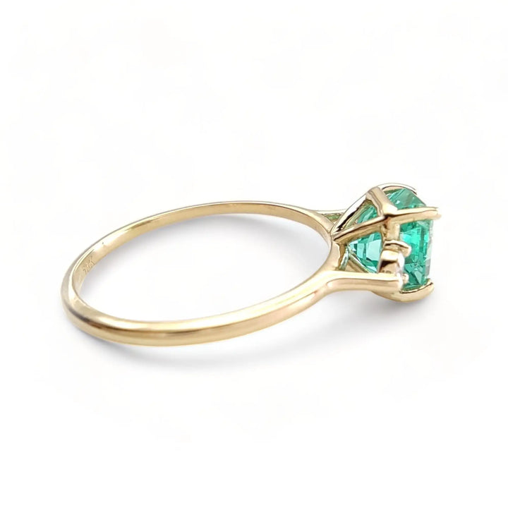 Right side view of a 18K yellow gold engagement ring with an octagon emerald and two brilliant-cut diamonds