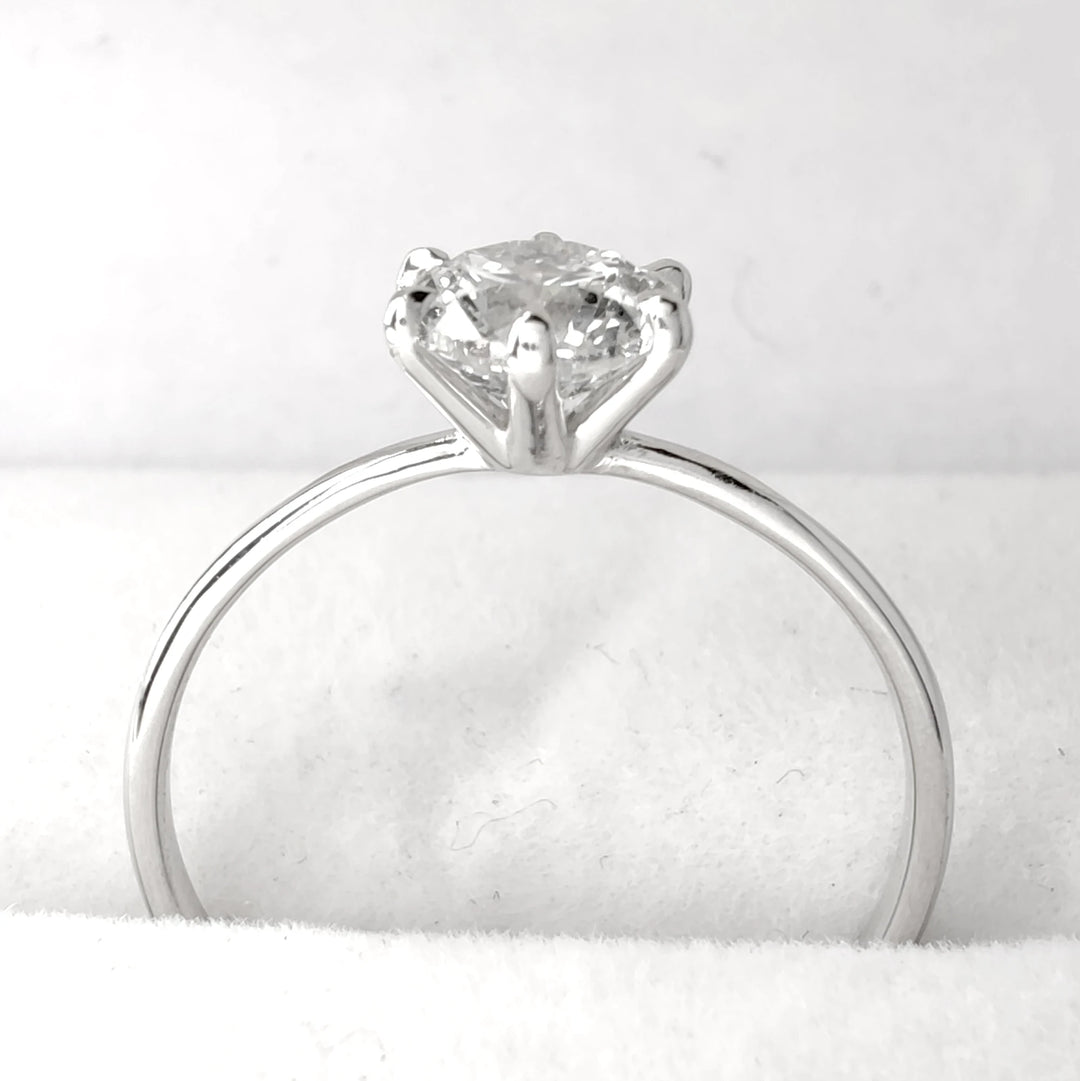 Diamond solitaire engagement ring displayed on soft white jewelry holder, 18k white gold