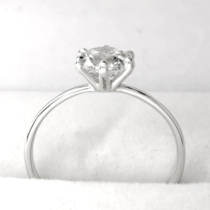 Diamond solitaire engagement ring displayed on soft white jewelry holder, 18k white gold