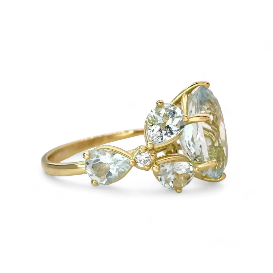 Right side horizontal view of a unique cocktail or engagement ring with an oval aquamarine, marquise gemstones, and diamond floral detailing