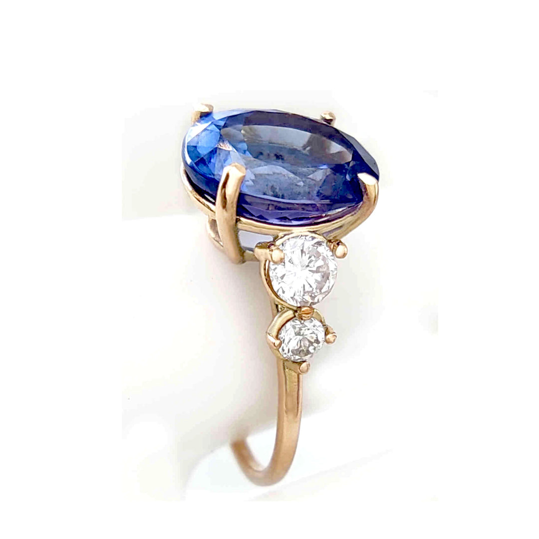 Close-up of a 14K yellow gold ring with Tanzanite and diamonds, showcased on a mannequin finger