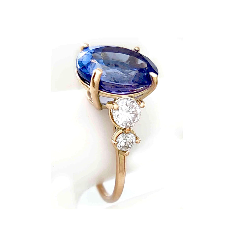 Close-up of a 14K yellow gold ring with Tanzanite and diamonds, showcased on a mannequin finger