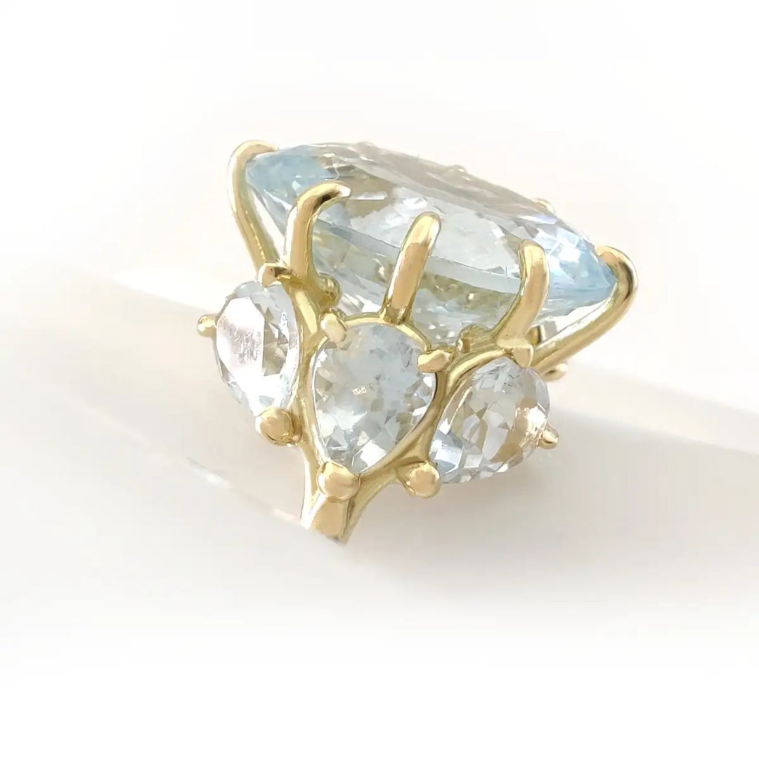 Image showcasing an innovative 18K gold engagement ring design, featuring a large oval aquamarine center and three pear-cut aquamarines on each side, highlighting the exploration of new design languages in gold rings with precious stones