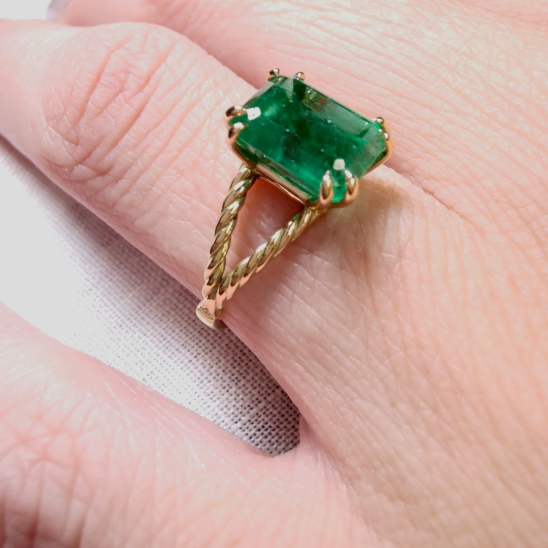 Close-up of an emerald engagement ring in solid 18K yellow gold, highlighting the green octagonal emerald, perfect as a Christmas gift or part of the emerald ring collection