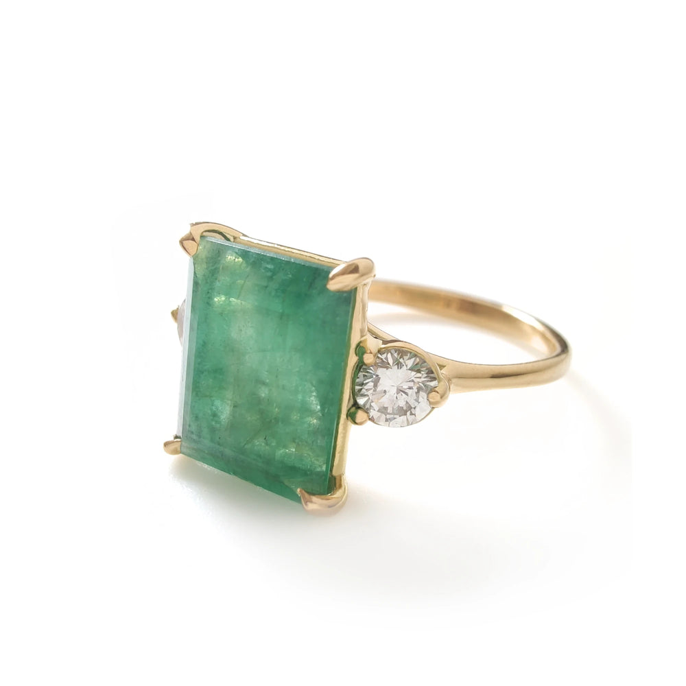 Angled close-up of large emerald ring with diamond sides in yellow gold