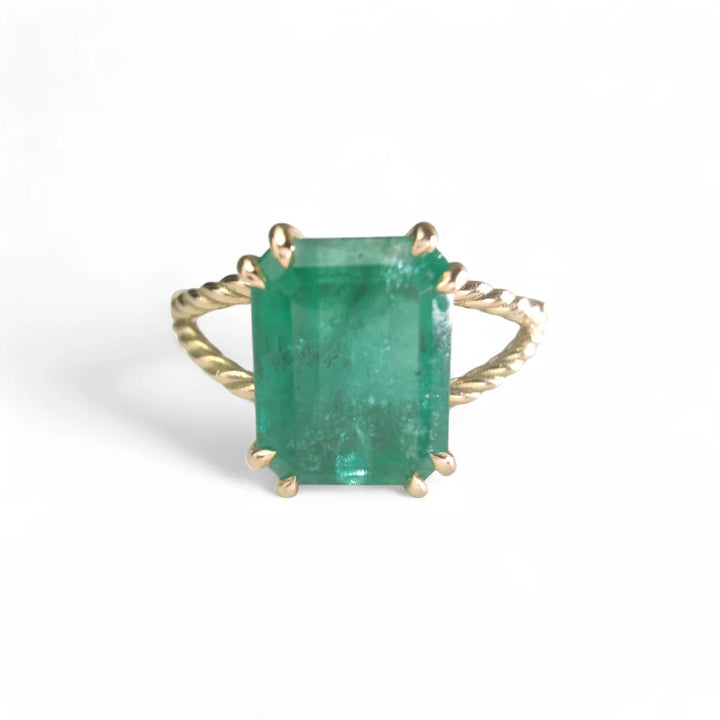 Frontal view of an 18K yellow gold engagement ring featuring a central octagonal green emerald, part of the emerald ring collection and a perfect Christmas gift