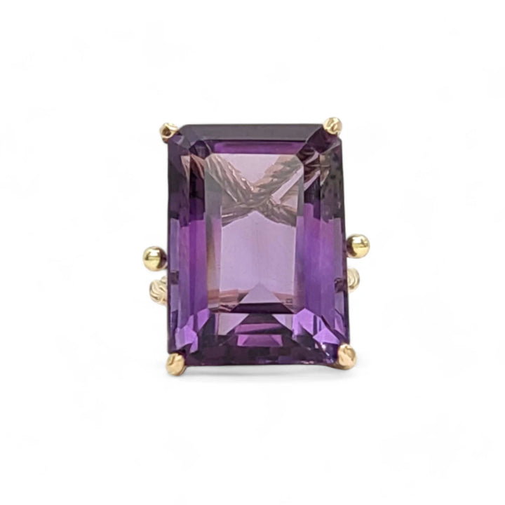 Front view of a handcrafted 14K yellow gold ring with a large amethyst centerpiece set in twisted prongs, designed for women who stand out