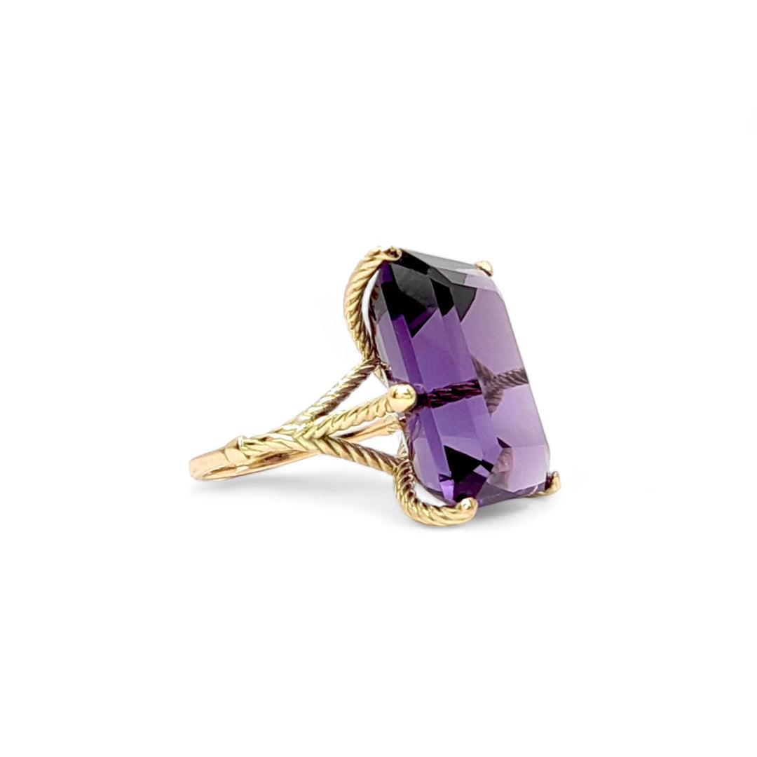 Right side view of a women’s 14K yellow gold ring with a large amethyst mounted in twisted prongs for an artistic and bold look