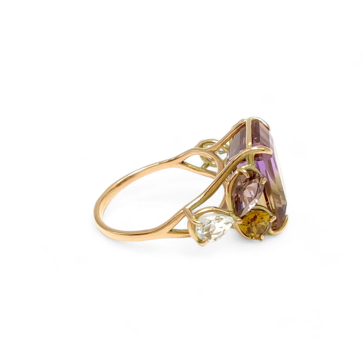 Horizontal right side view of a bold cocktail ring in 14K yellow gold featuring an emerald-cut ametrine, amethysts, and aquamarines