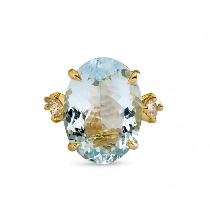 Front view of a three-stone engagement ring in 18K yellow gold featuring an oval aquamarine centerpiece and two brilliant-cut diamonds