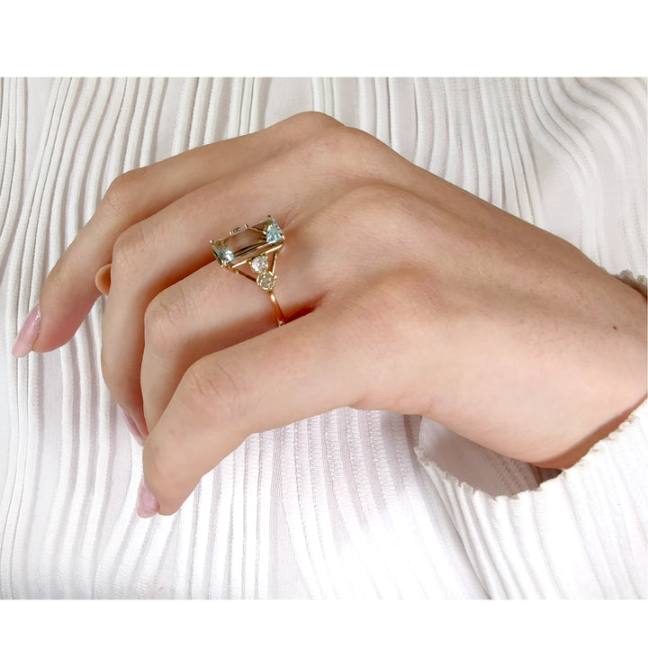 Beautiful emerald-cut aquamarine ring with diamonds in 14K yellow gold displayed on a model’s hand in pose 3