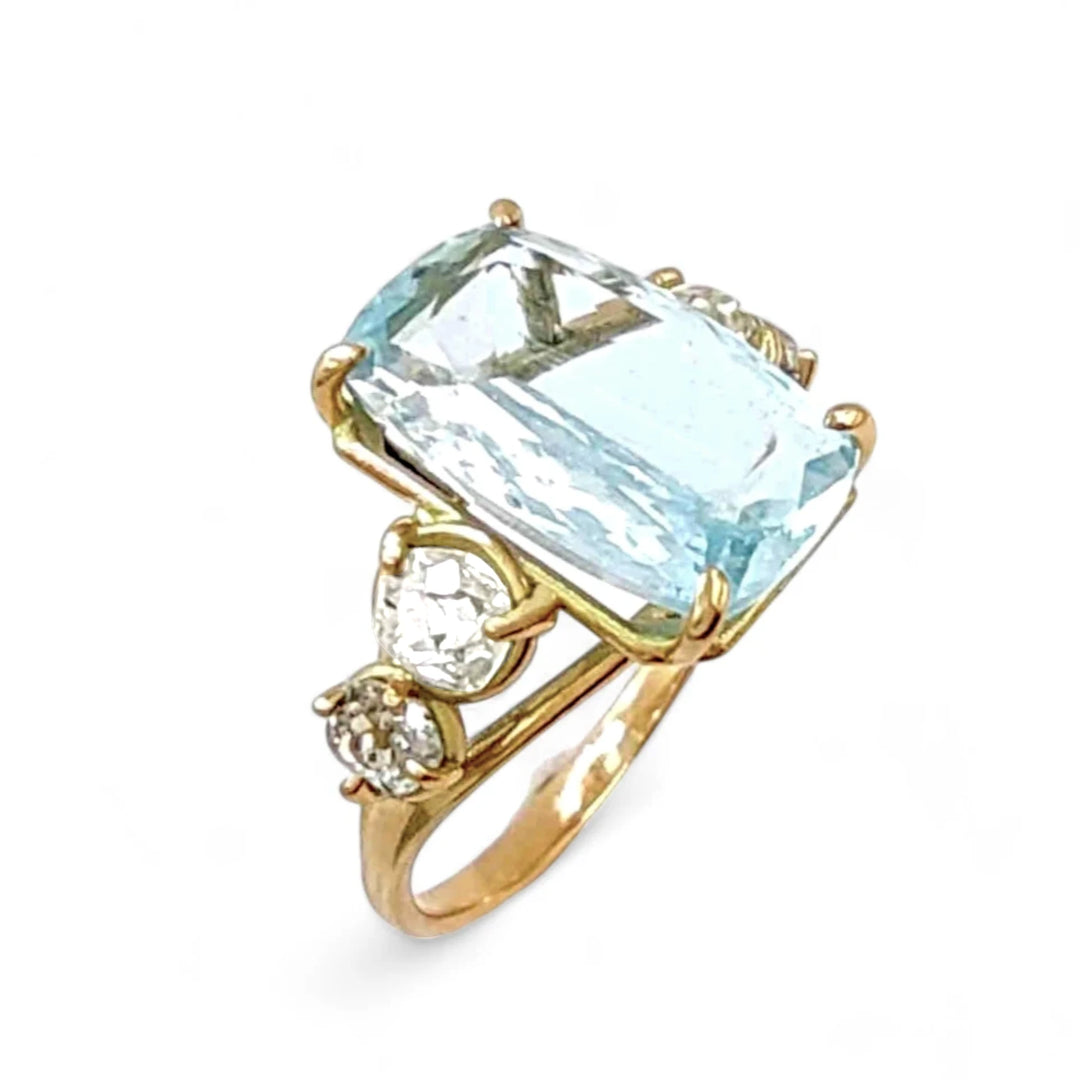 Perspective view of a 14K solid yellow gold ring with a cushion-cut aquamarine and two brilliant-cut diamonds on each side