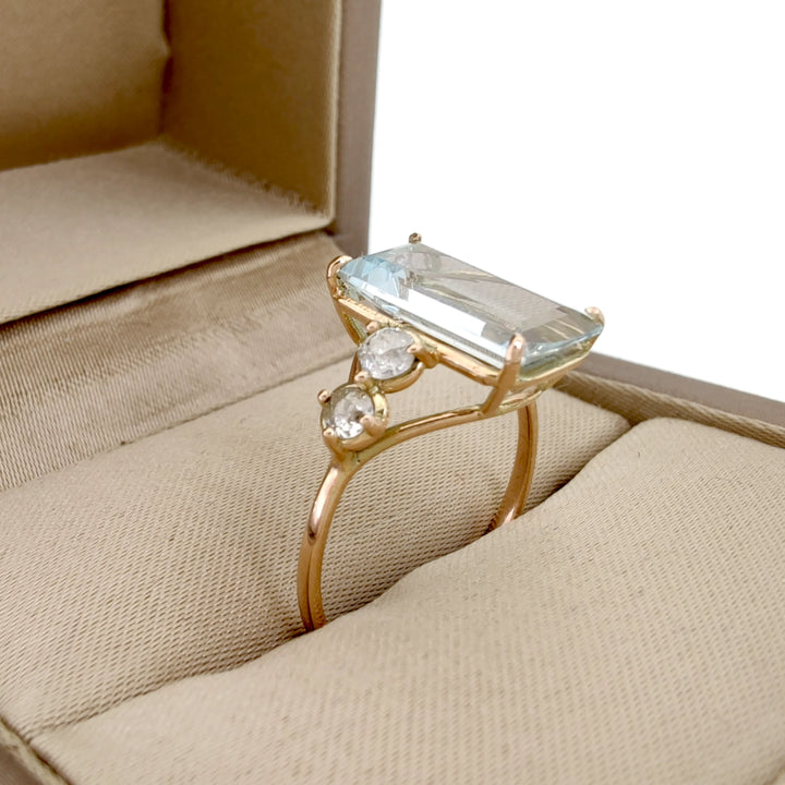 Elegant emerald-cut aquamarine engagement ring with diamonds in 14K yellow gold displayed inside a jewelry gift box

