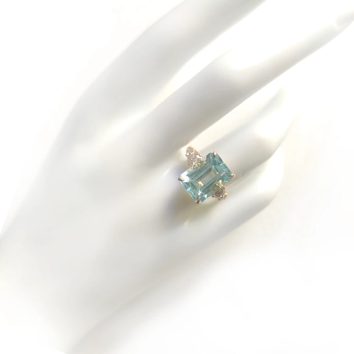 full view of a women’s 18K yellow gold cocktail ring with aquamarine and diamonds displayed on a mannequin hand