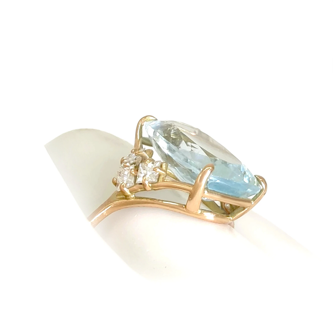 Detailed lateral view of a handcrafted 14K yellow gold ring featuring a rectangular cushion aquamarine and V-shaped diamond arrangement displayed on a mannequin