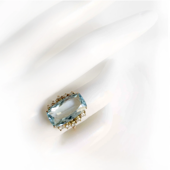 Elegant 14K yellow gold engagement ring with a cushion-cut aquamarine and diamond accents displayed on a mannequin hand