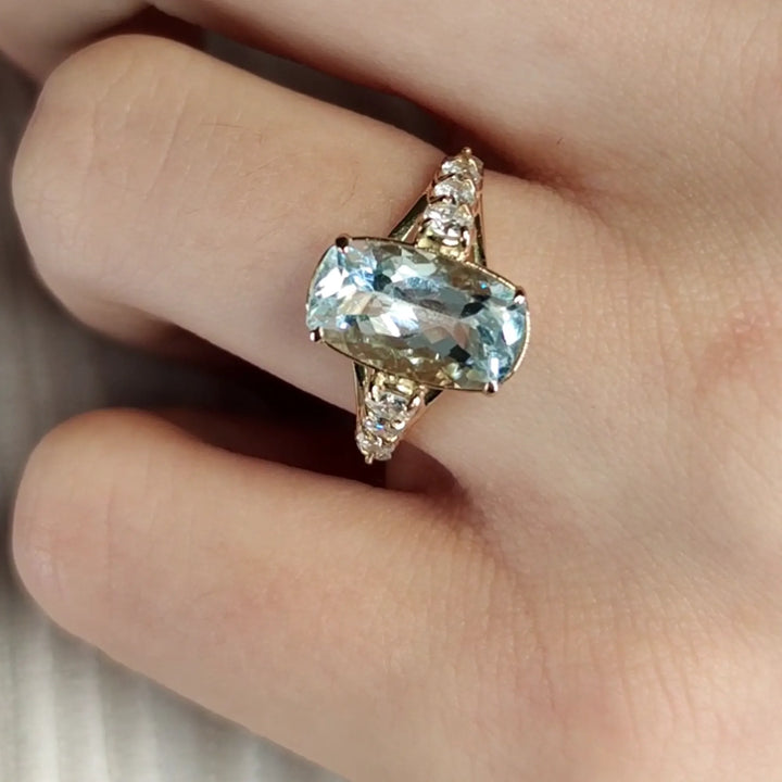 Stunning cushion-cut aquamarine and diamond ring in 14K yellow gold, worn on a female model’s hand, ideal for engagement or cocktail occasions, perfect gift