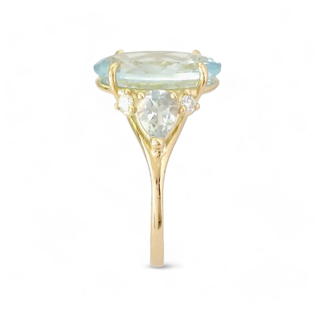 vertical side view of a stunning 18K yellow gold engagement ring with an oval aquamarine centerpiece, pear-shaped aquamarines, and diamonds