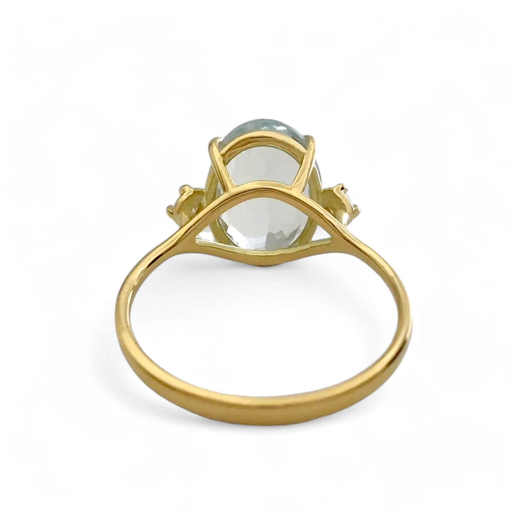 Back view of a timeless 18K yellow gold three-stone engagement ring featuring a central aquamarine and diamond details