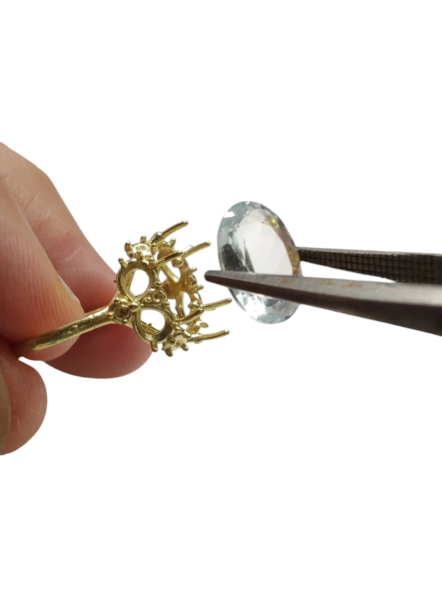 Image of a jeweler meticulously crafting an engagement ring featuring an aquamarine center stone and diamond accents, showcasing the artistry and precision of fine jewelry making.