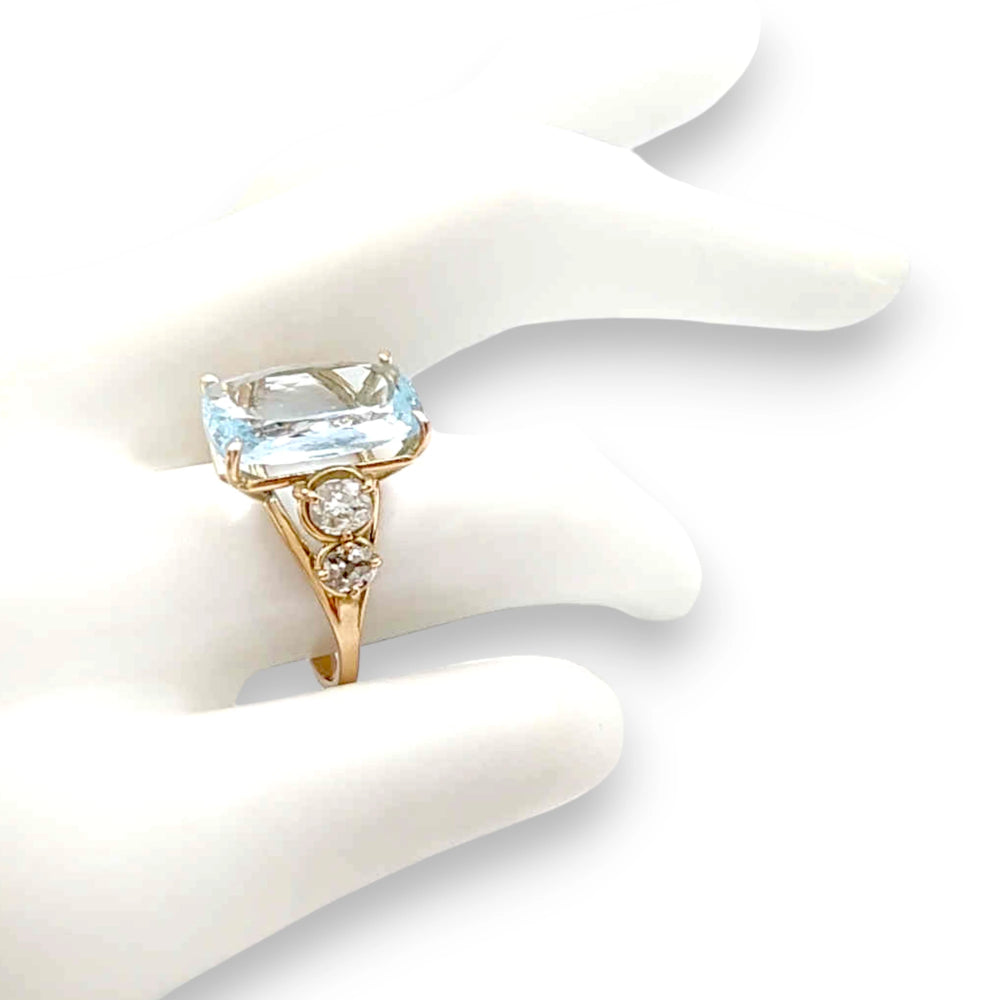 14K yellow gold ring with a central cushion-cut aquamarine and diamonds, displayed on a mannequin hand
