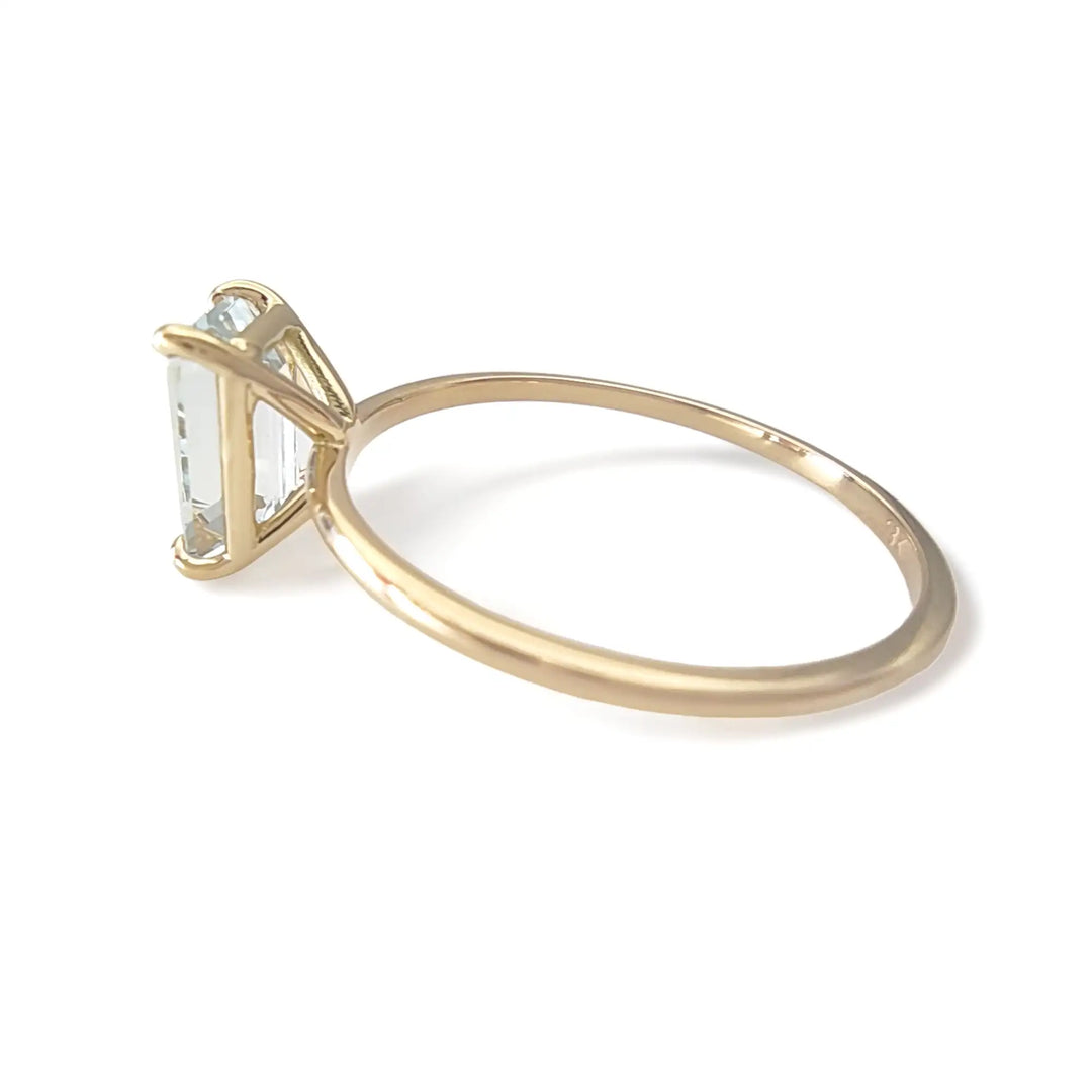 Left side view of a solitaire 18K yellow gold ring with a central aquamarine