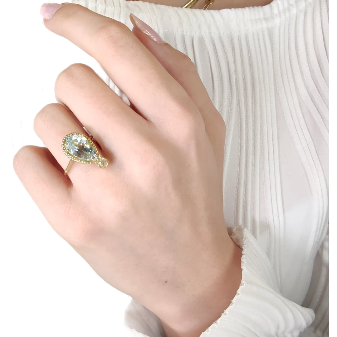 Stunning pear-cut aquamarine and diamond engagement ring in 18K yellow gold worn by a model