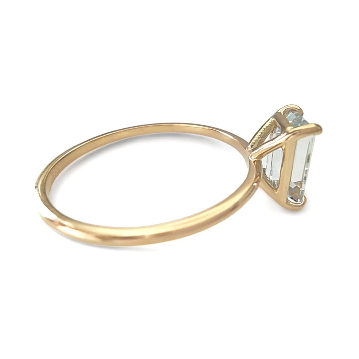 Right side view of a minimalist solitaire ring in 18K yellow gold with a central aquamarine