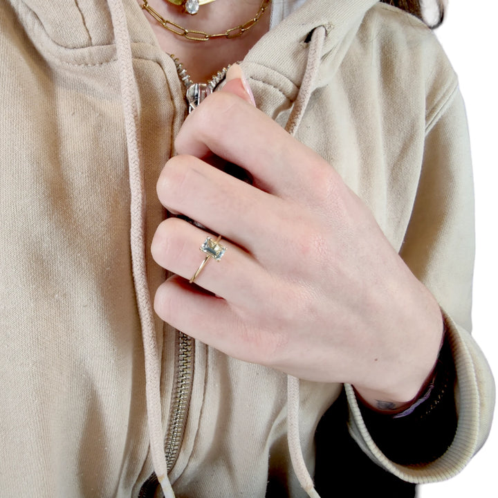 Minimalist solitaire aquamarine ring in 18K yellow gold worn by a female model