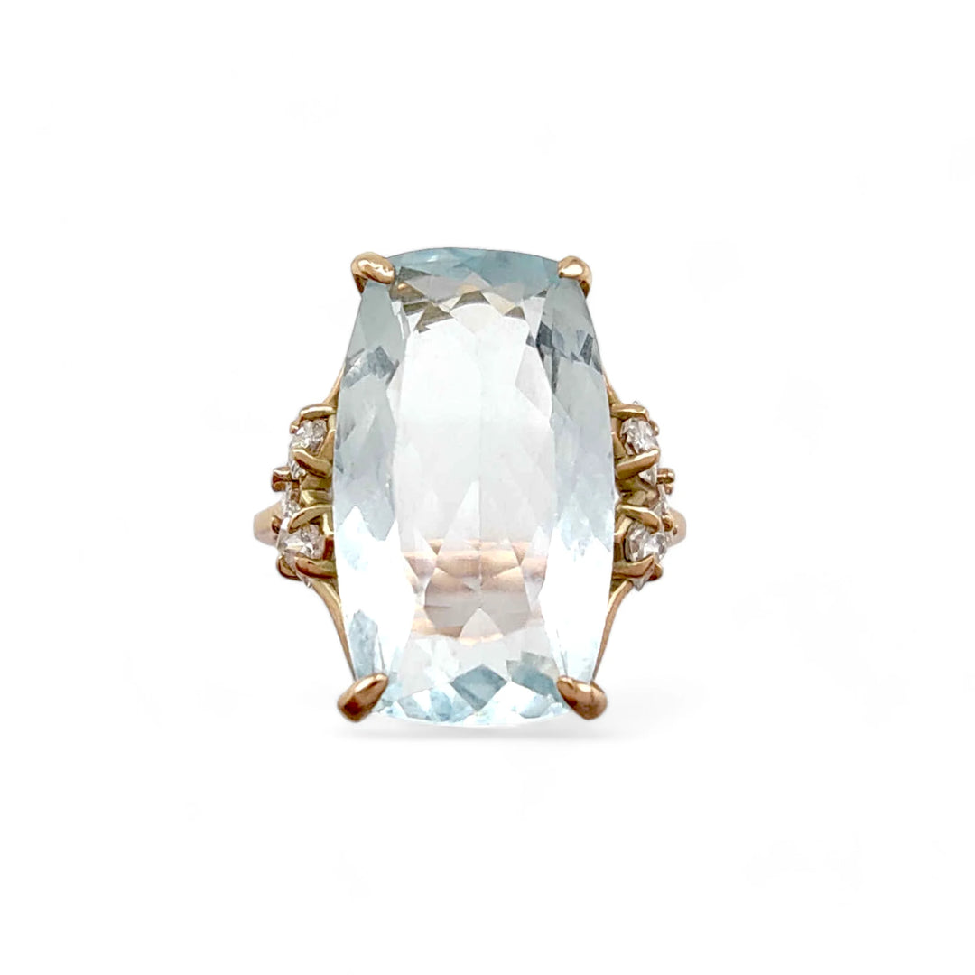 Front view of an artistic 14K yellow gold ring with a rectangular cushion aquamarine centerpiece and diamond accents in a unique V-shaped design