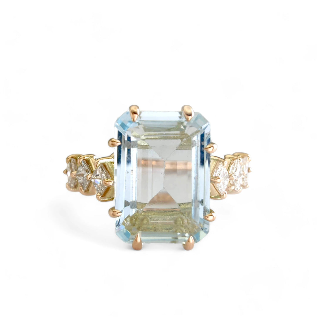 Front view of a unique 14K yellow gold ring featuring a large aquamarine centerpiece and three princess-cut diamonds on each side, ideal for proposals or Christmas gifts